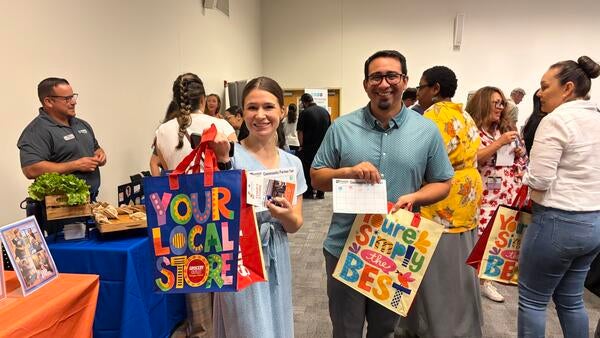 UCR staff showing off their tote bags and stamp rally card.