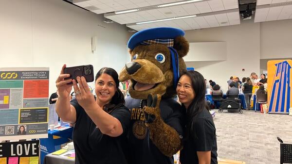 Community Partner Fair vendors take a selfie with Scotty Bear.
